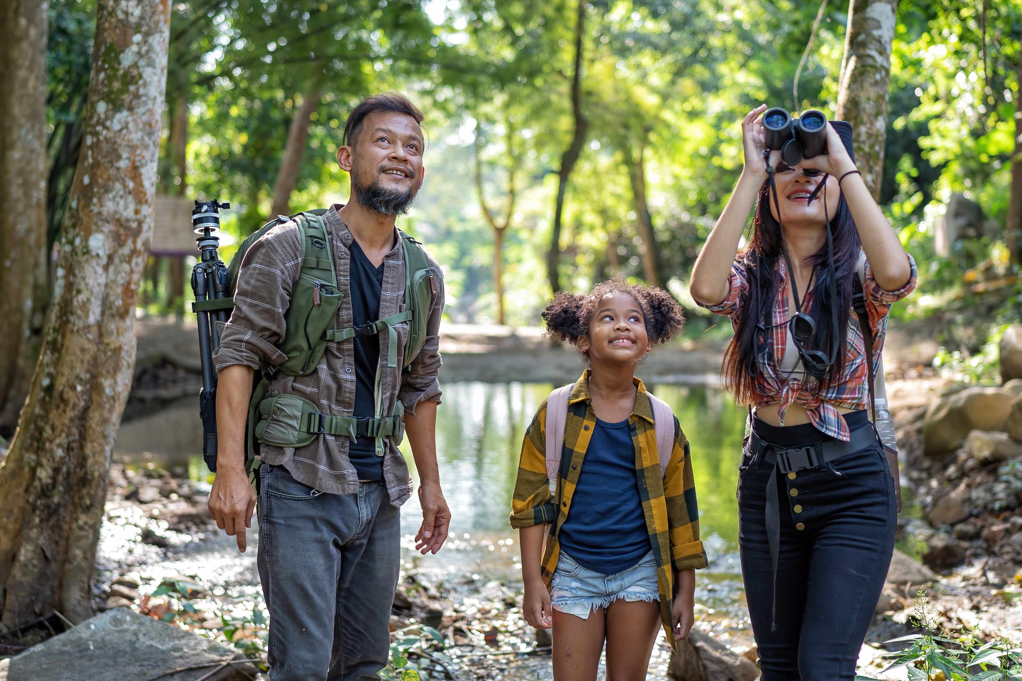 Backpack traveller family with little girl outdoor adventure bird study using binoculars