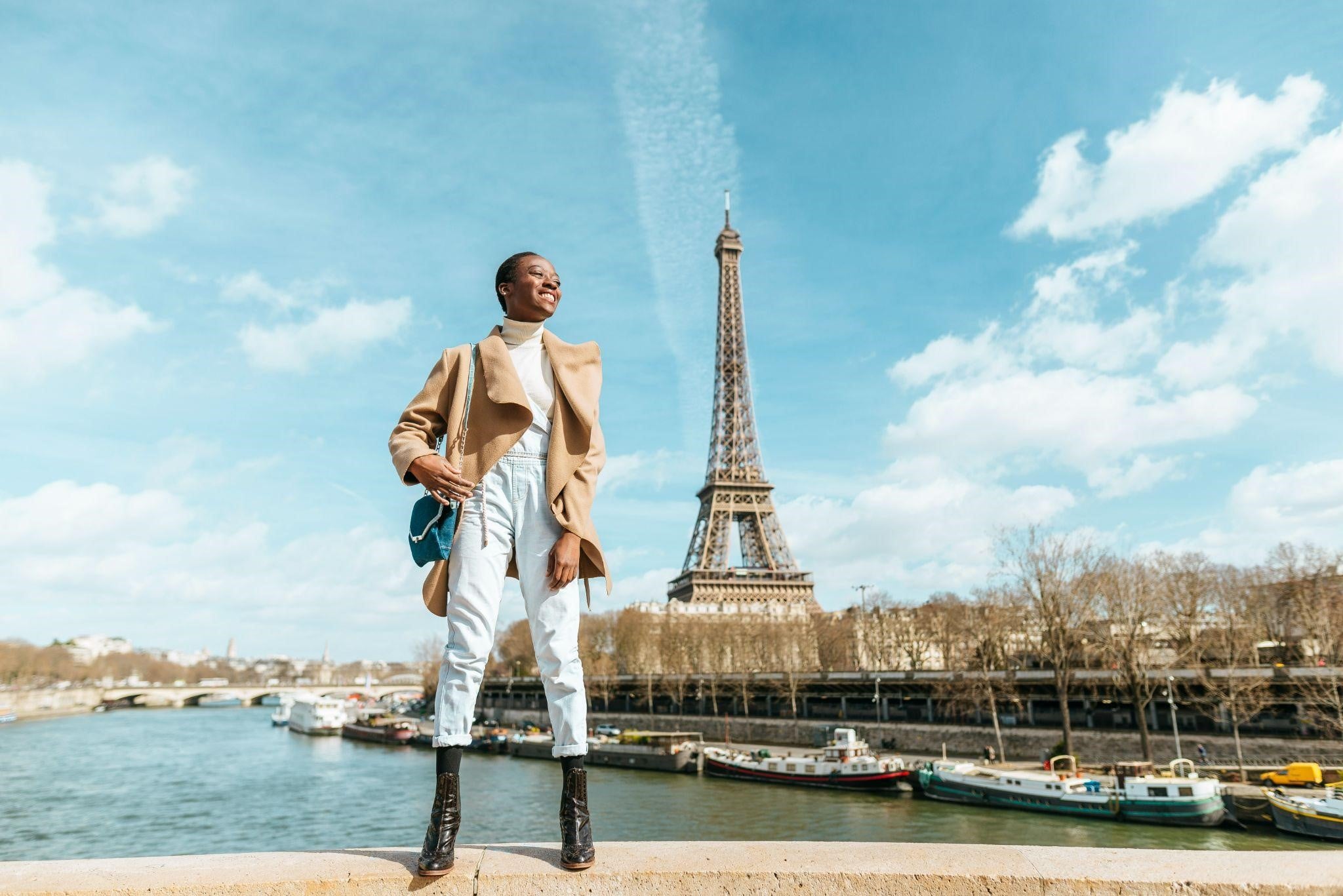 Smiling woman standing on a bridge with the Eiffel Tower in the background