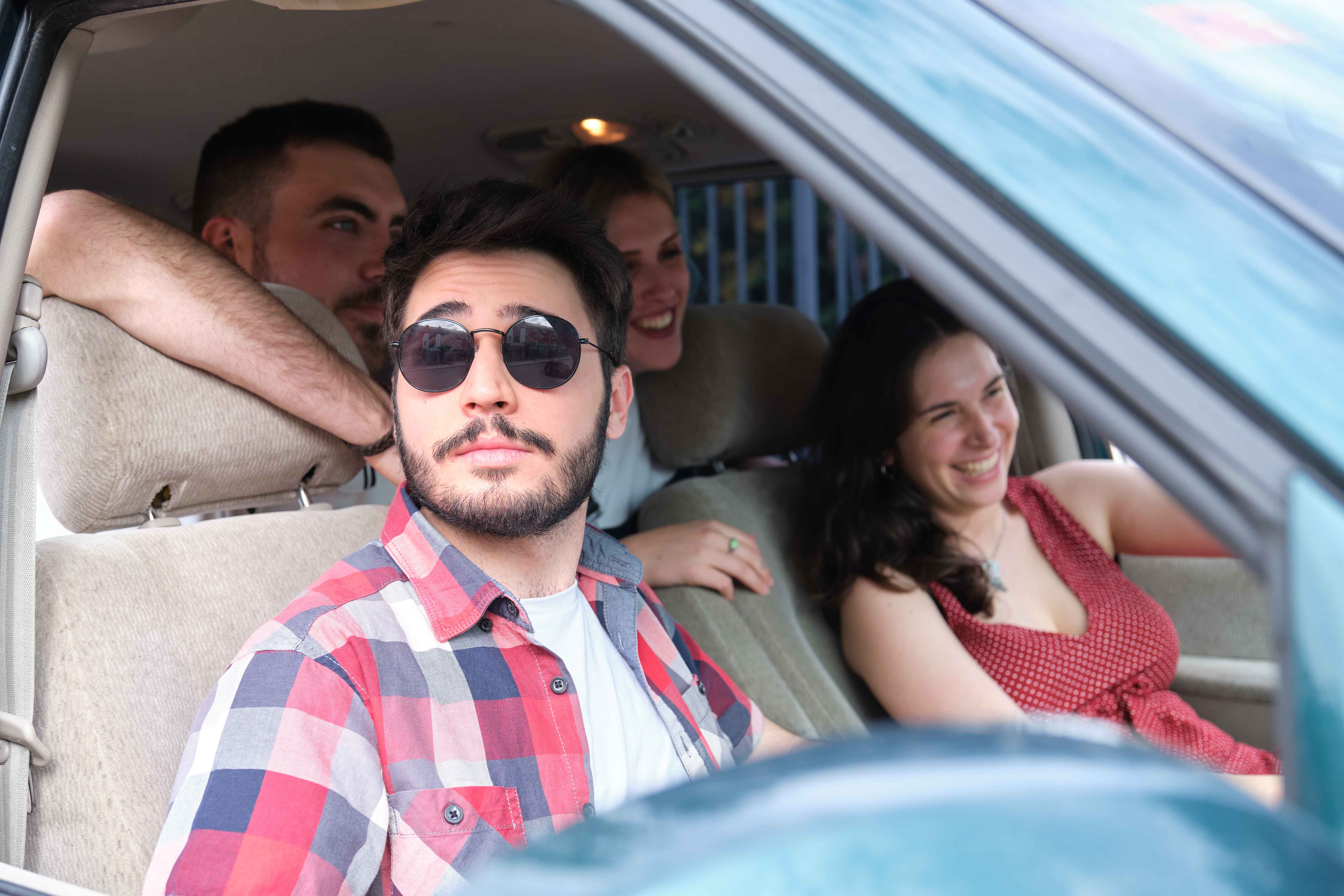 Group of friends travel together driving a car and making fun